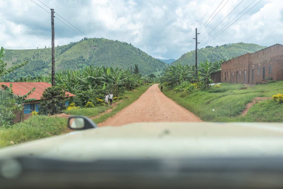 A Landcruiser traveling along a scenic road to Bwindi Impenetrable National Park, with lush greenery and mountainous terrain in the background.